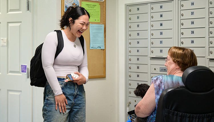 A standing woman talks to an older woman in a wheelchair A standing woman talks to an older woman in a wheelchair