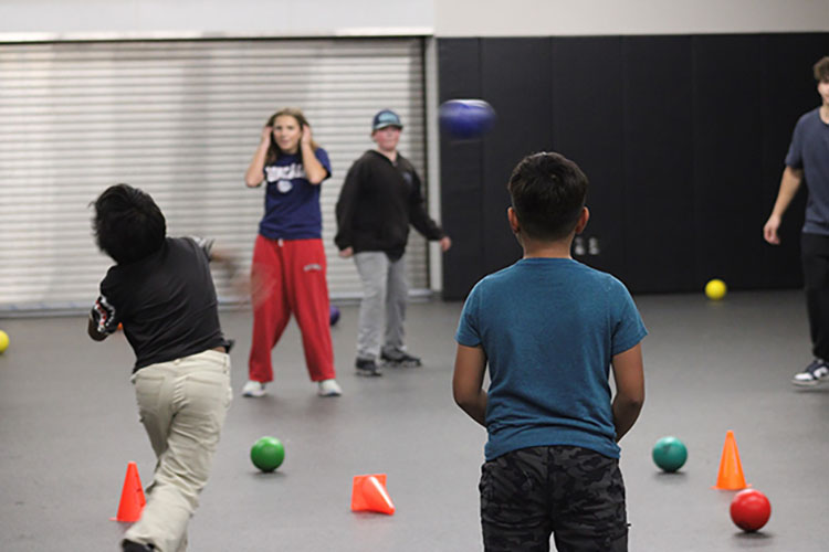 Four students playing a game with small green balls and orange cones.