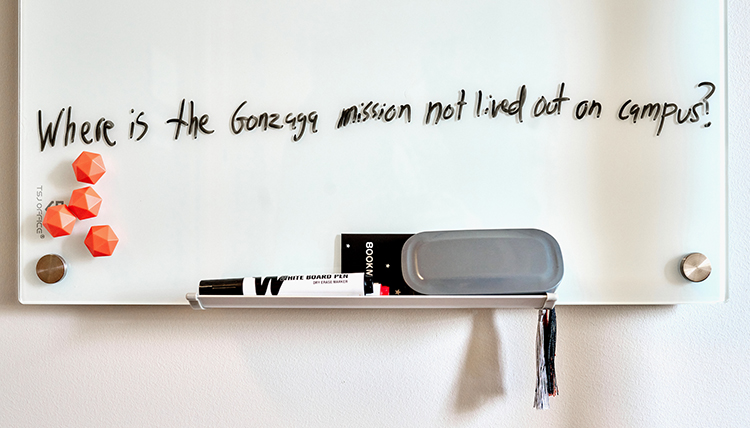 A white board that says Where is the gonzaga mission not lived out on campus?