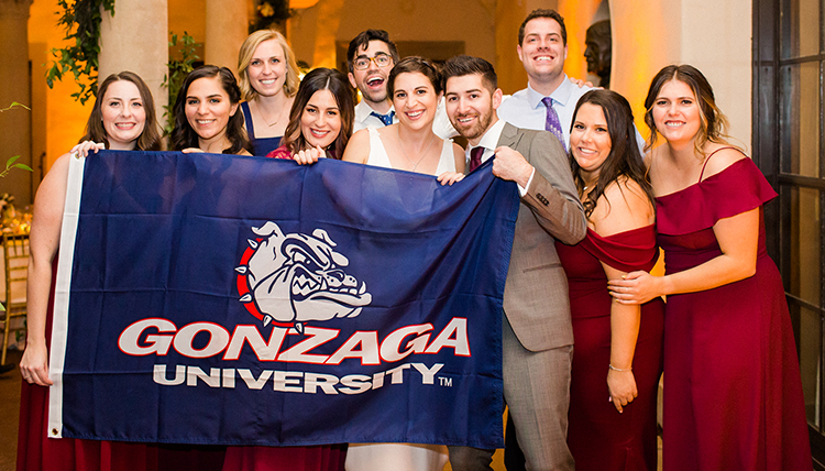 group of Zags around couple with Gonzaga flag group of Zags around couple with Gonzaga flag