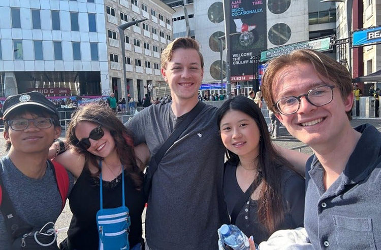 Five young adults stand on a large city street