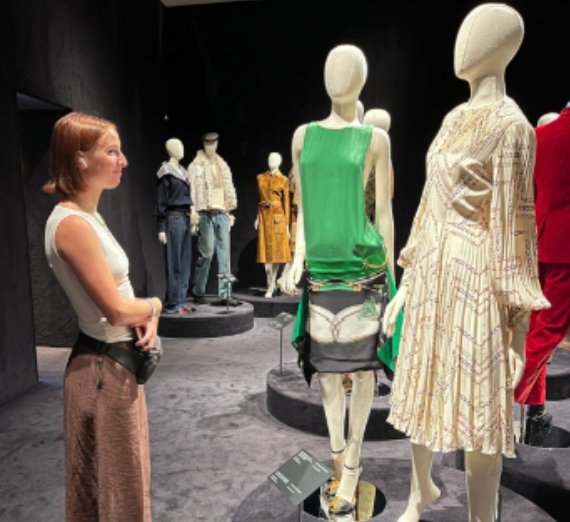Student admiring Gucci & Ferragamo clothing in a showroom.