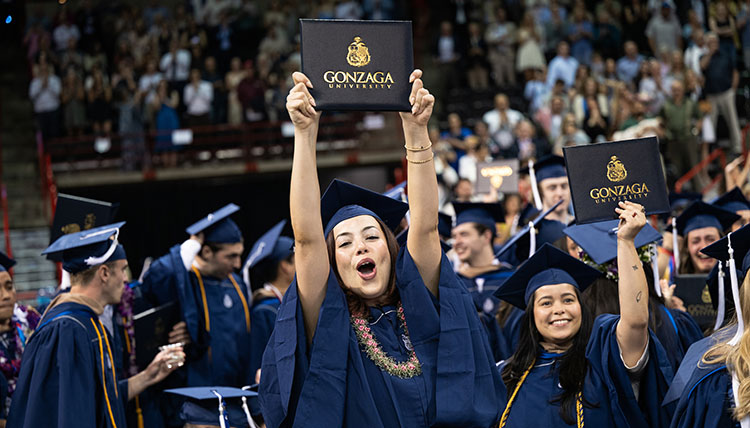 Two women hold up their degrees Two women hold up their degrees