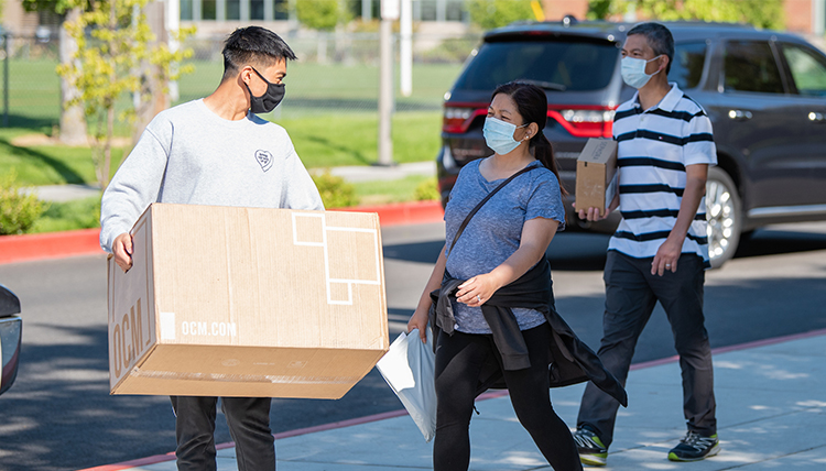 a student and parents carry items to dorm a student and parents carry items to dorm