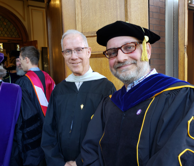 Fr. Ken Krall and Dr. David Oosterhuis in academic regalia at the entrance of St. Aloysius Catholic Church.