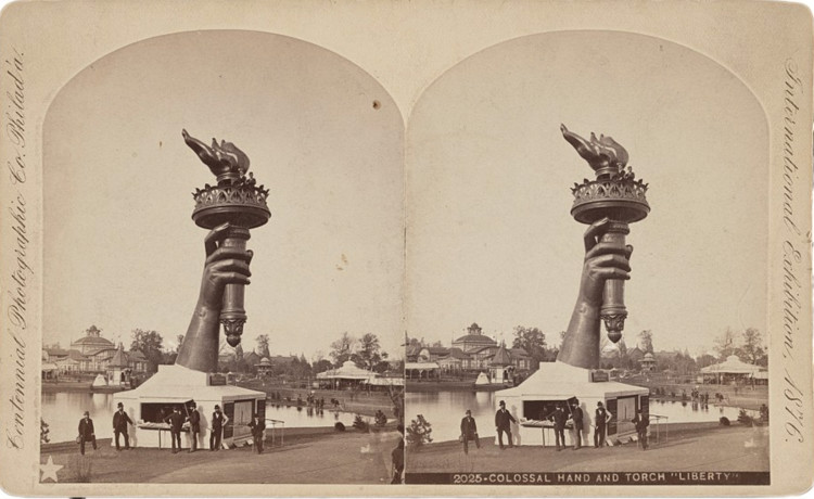 Library-of-Congress-Colossal-hand-and-torch-Liberty-750x460.jpg Photograph shows the torch and part of the arm of the Statue of Liberty, on display at the 1876 Centennial Exhibition in Philadelphia. Information booth at base of arm and two persons seen at railing below flame of torch.