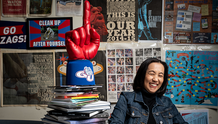 shiosaki at her desk with piles of memorabilia around her A group of students collaborate about a story around a table.