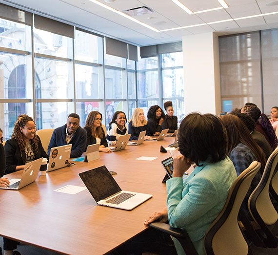 Large group meeting around meeting table.