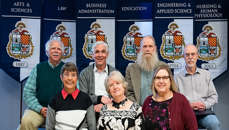 four men stand behind three women, all faculty four men stand behind three women, all faculty