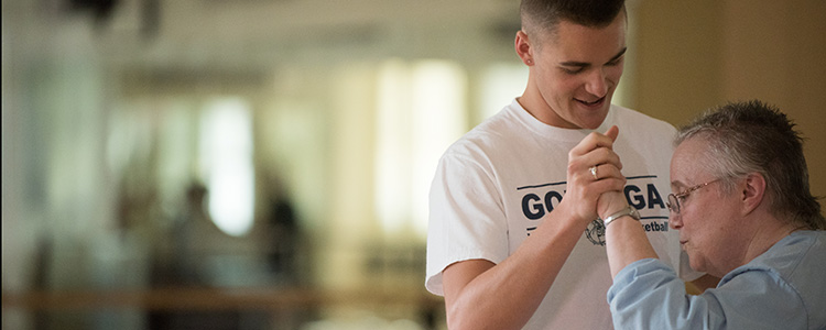 Gonzaga student smiles and dances with Parkinson’s dance participant. Gonzaga student smiles and dances with Parkinson’s dance participant.