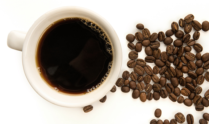 A cup of black coffee is shown alongside coffee beans. A cup of black coffee is shown alongside coffee beans.