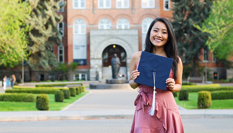 Gonzaga Alumni Allana Platt stands in front of College Hall holding a graduation cap. Gonzaga Alumni Allana Platt stands in front of College Hall holding a graduation cap.