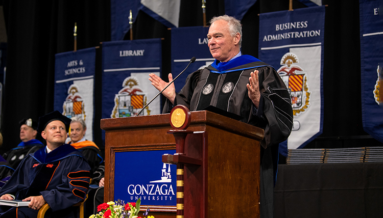 A man speaks at a podium while another man looks on A man speaks at a podium while another man looks on