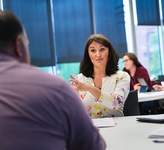 A woman talks to a man across a round table