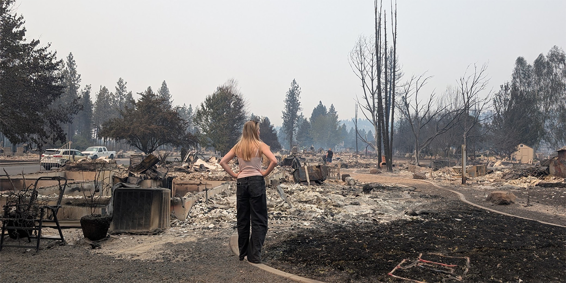 A woman stands in the ashes of a burned house