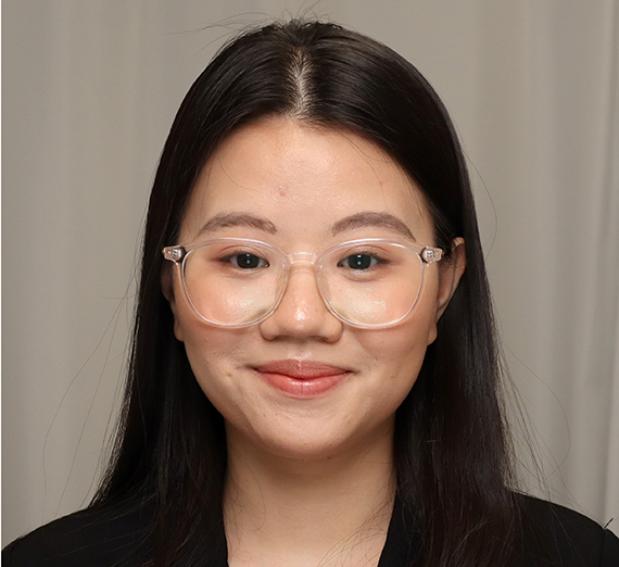 headshot of female with long dark hair and wearing glasses, smiling at the camera