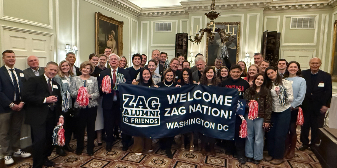Attendees of the Forging Forward Washington, D.C. presidential event hold up a banner that with the Zag Alumni & Friends logo and text Attendees of the Forging Forward Washington, D.C. presidential event hold up a banner that with the Zag Alumni & Friends logo and text