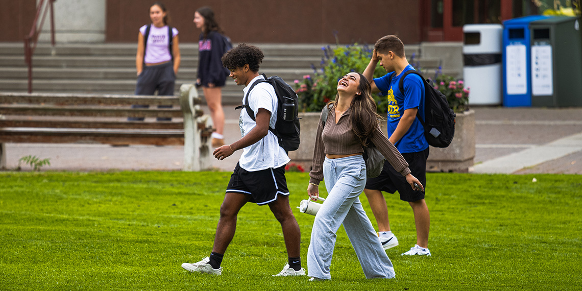 Students walking across grass on campus.