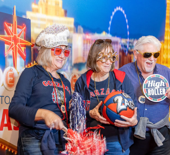 Attendees of the ZagUp event at the WCC Basketball Tournament in Las Vegas pose with props in front of a Vegas-themed background. Attendees of the ZagUp event at the WCC Basketball Tournament in Las Vegas pose with props in front of a Vegas-themed background.