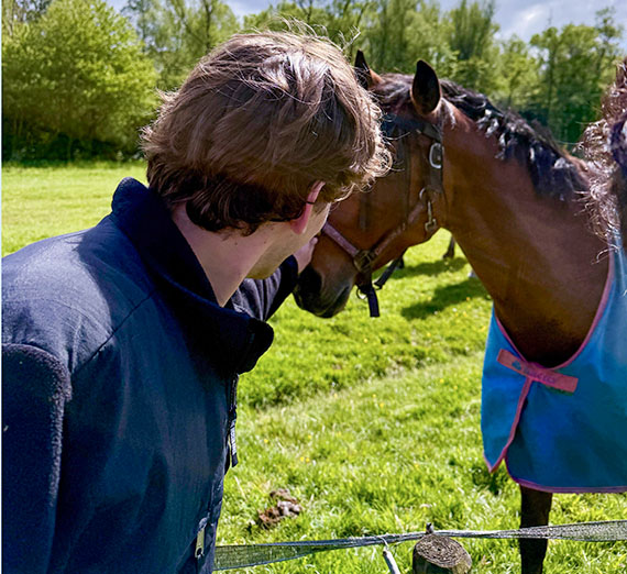 Young man pets a horse