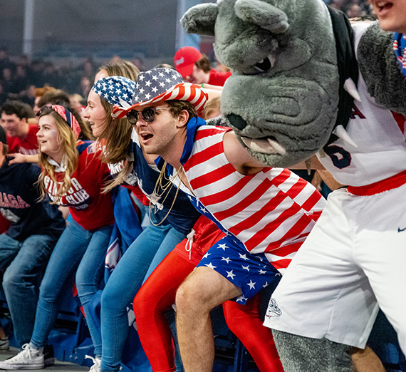 Gonzaga University students with their faces painted cheering in the Kennel Club student section at a basketball game
